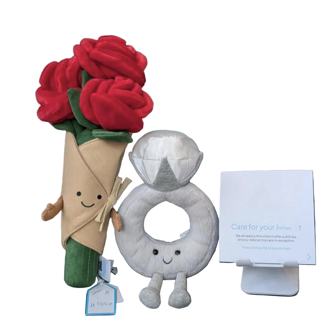 Plush toy roses and a plush ring with a face on a chair next to a blue drawstring bag.